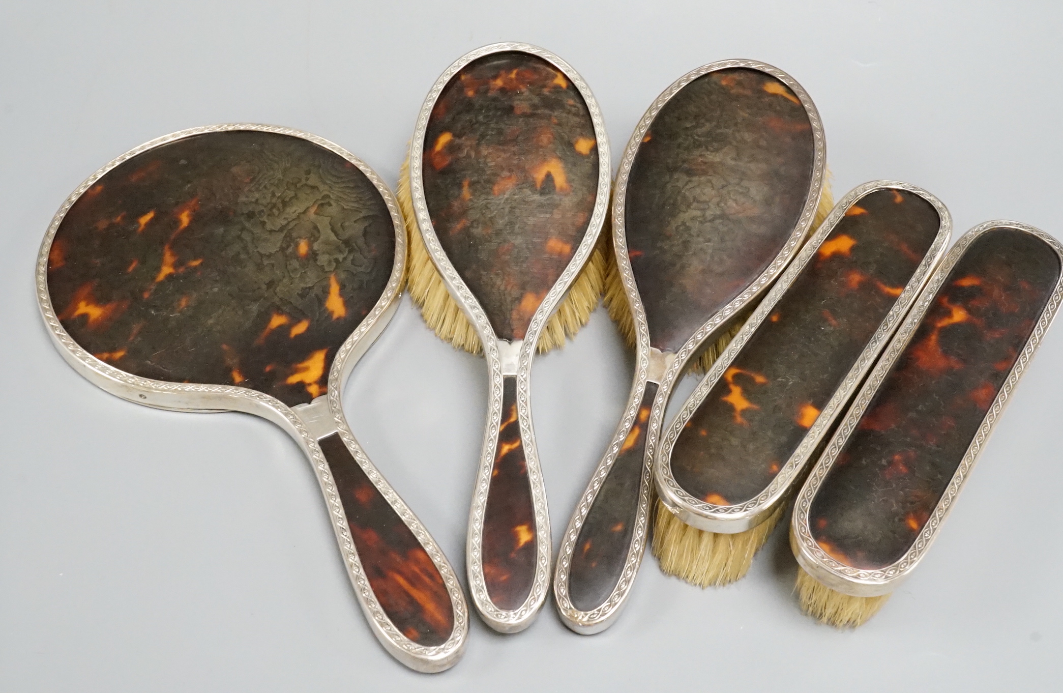 A 1940's silver and tortoiseshell mounted five piece mirror and brush set.